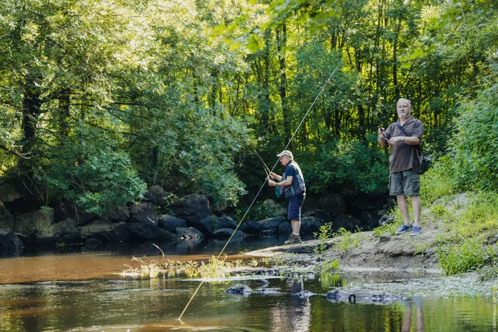 Deux pecheurs au bord d'un lac verdoyant